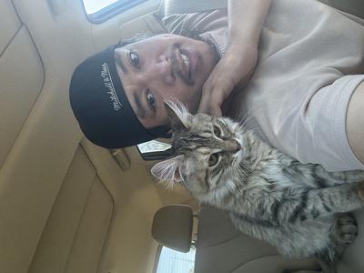 Jose and Suki young man and his cat together in a vehicle smiling.